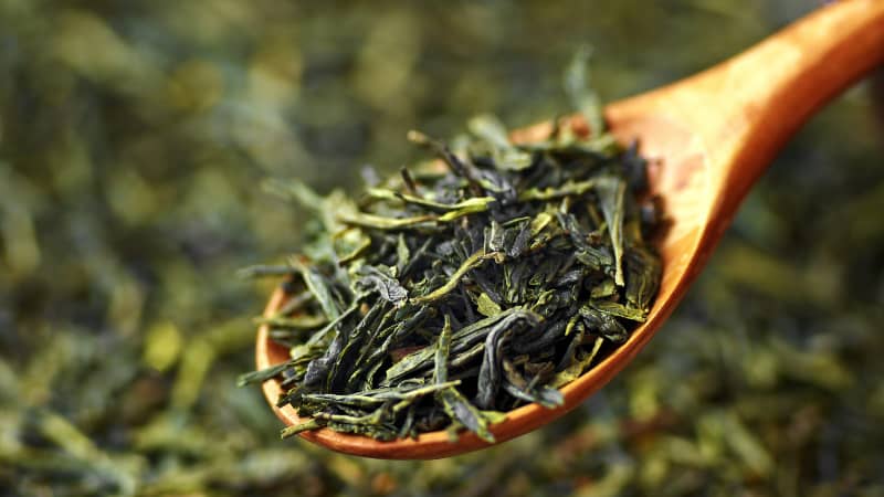 چای سبز اصل لاهیجان در یک قاشق چوبی؛ مرتبط با چای ایرانی خوبه یا خارجی