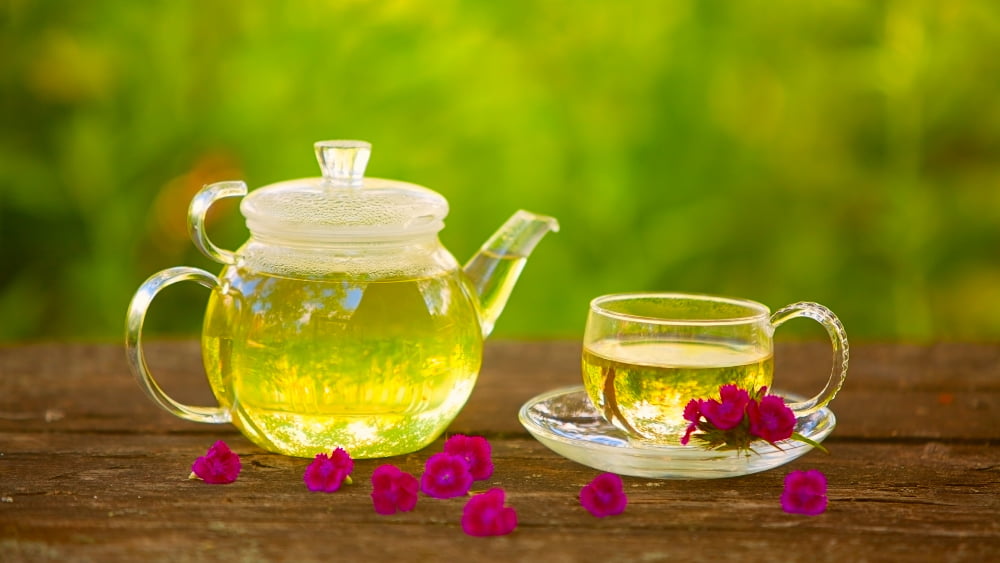 یک قوری و فنجان شیشه ای چای سبز