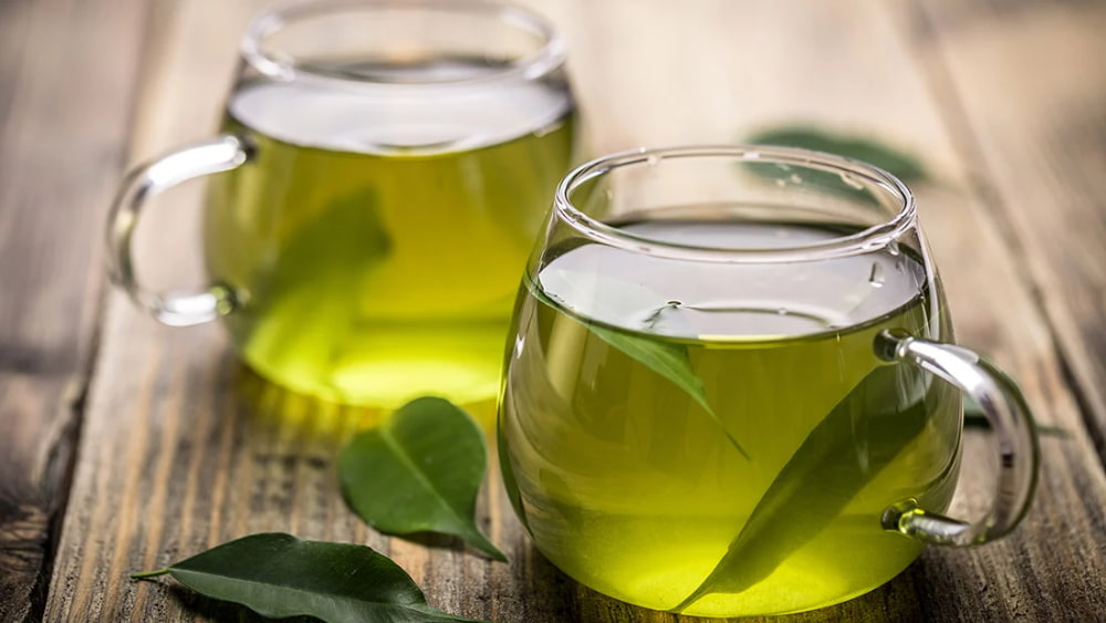 دو لیوان دسته دار شیشه ای حاوی چای سبز