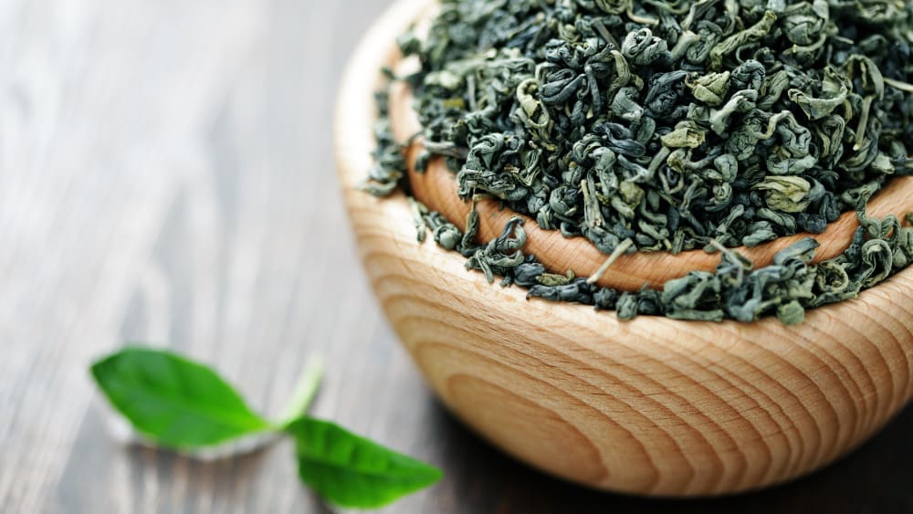 چای سبز خشک داخل کاسه چوبی