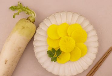دانموجی یا ترشی تربچه کره ای در یک ظرف همراه با ترب خام