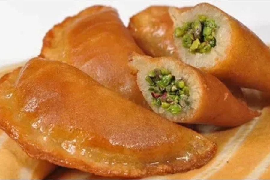 عکس نمای نزدیک از شیرینی قطایف عربی با مغز پسته، دسر خوشمزه ماه رمضان.