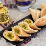 قطایف لبنانی تازه و خوشمزه با مغز خامه و پسته، آماده سرو در کنار چای عربی.