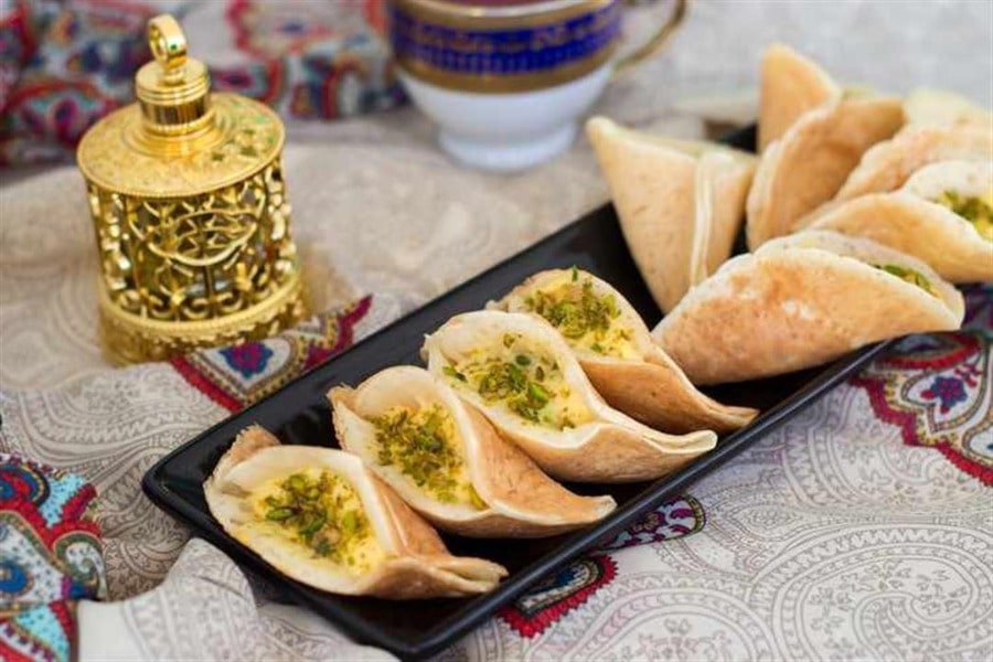 قطایف لبنانی تازه و خوشمزه با مغز خامه و پسته، آماده سرو در کنار چای عربی.