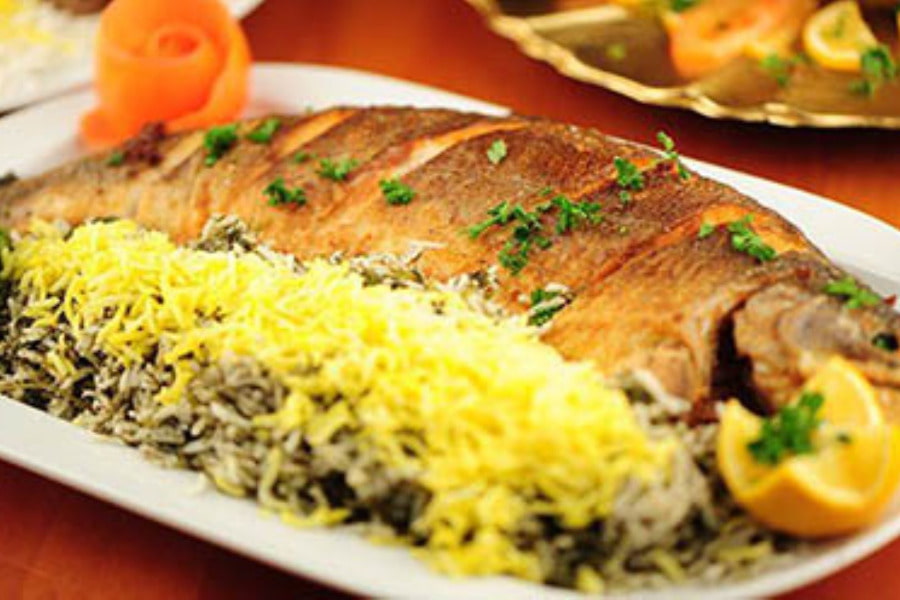 یک بشقاب سبزی پلو با ماهی سرخ شده، تزئین شده با برنج زعفرانی، لیموترش و جعفری