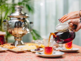 زنی در حال ریختن چای از قوری داخل استکان کمر باریک