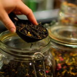 چای خشک در قاشق پلاستیکی و ظرف شیشه ای