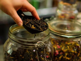 چای خشک در قاشق پلاستیکی و ظرف شیشه ای