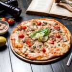 پیتزا تن ماهی با لیمو و چنگال و چاقو روی میز