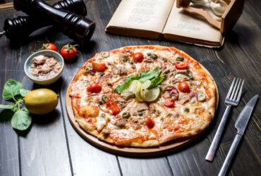 پیتزا تن ماهی با لیمو و چنگال و چاقو روی میز